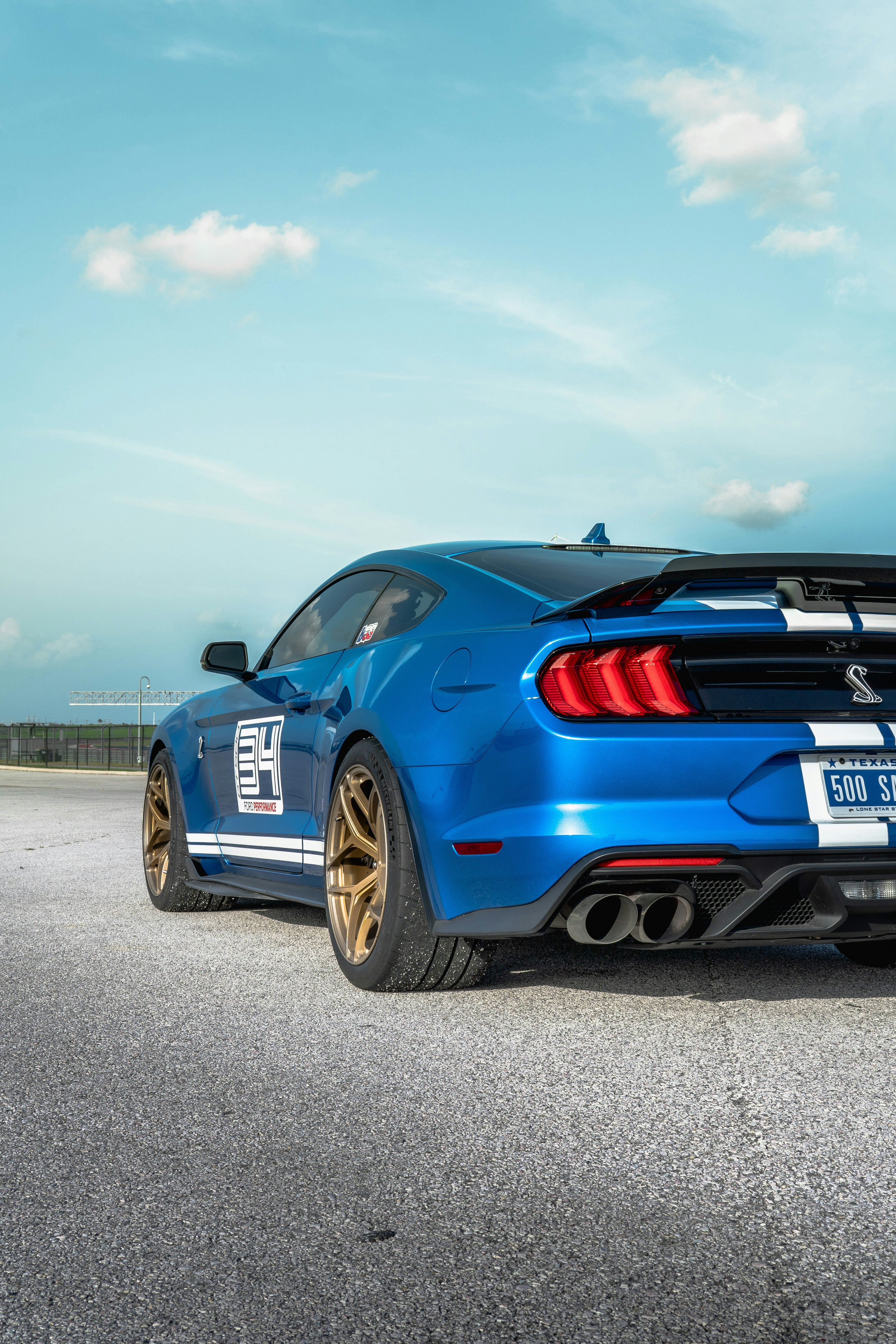 Dark blue Ford Mustang GT500 with wide body kit and aggressive stance at a car meet