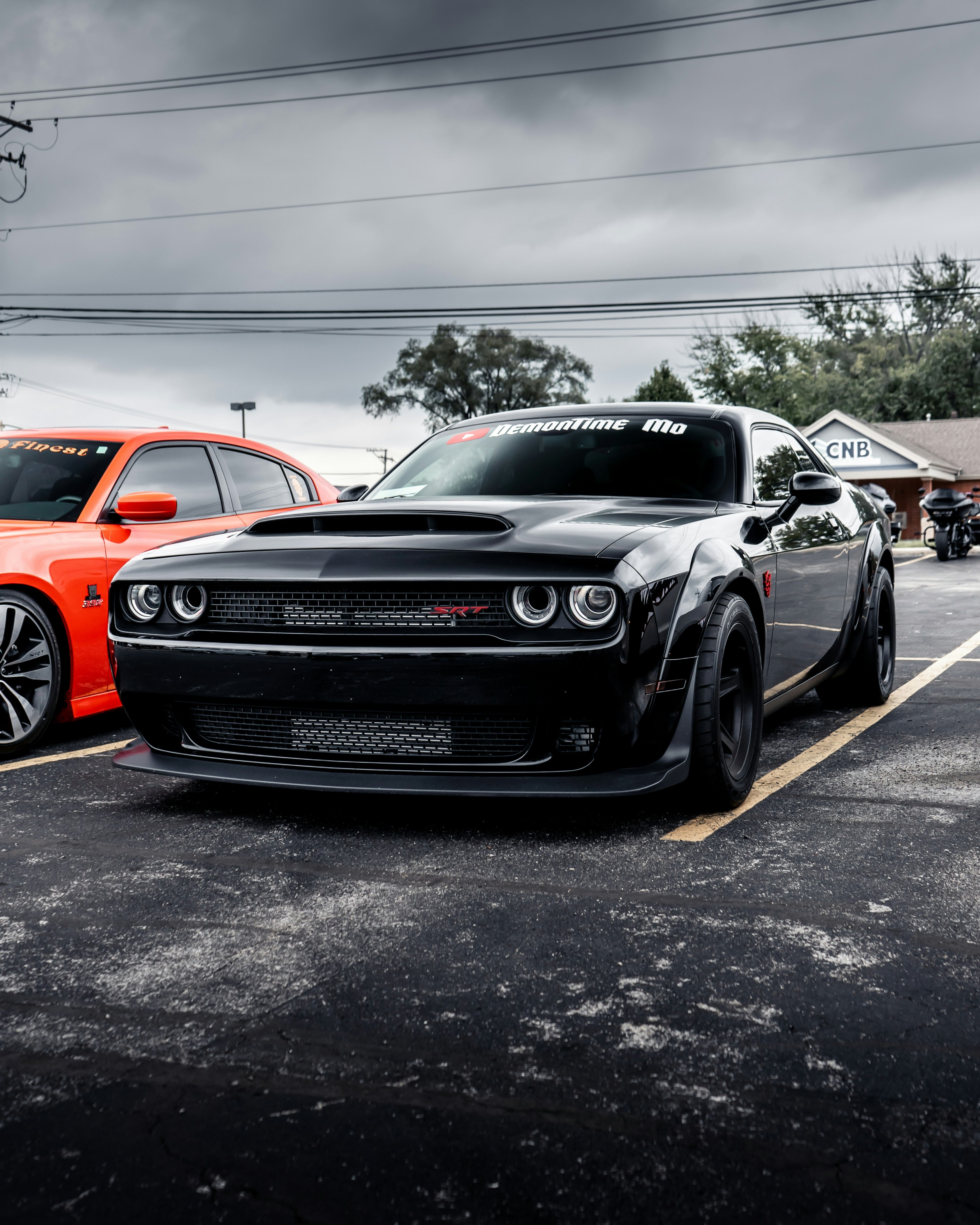 Orange Dodge Challenger Hellcat Widebody parked at a car show with crowd in background