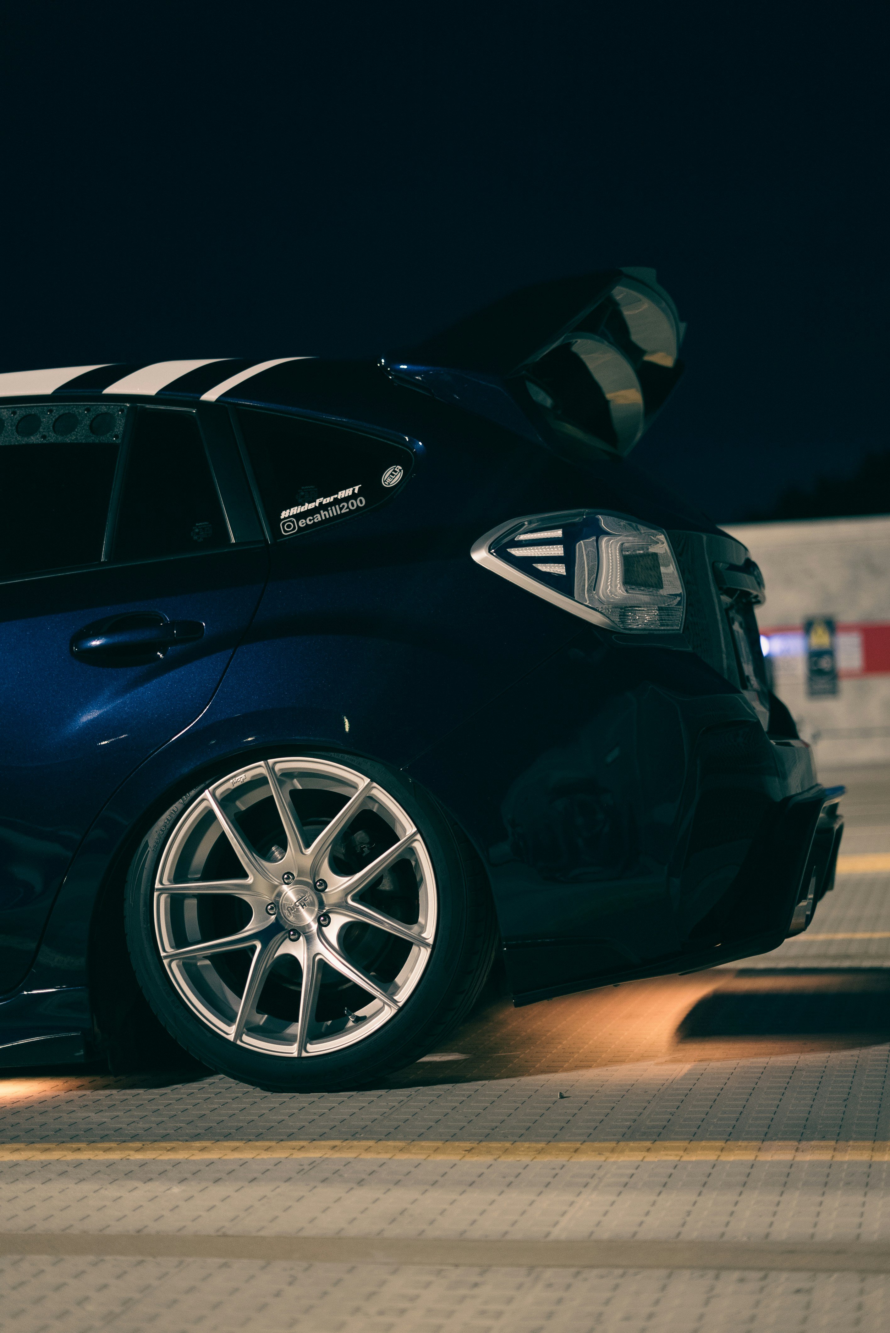 Blue Subaru WRX STI with aftermarket wheels and lowered suspension at a night meet