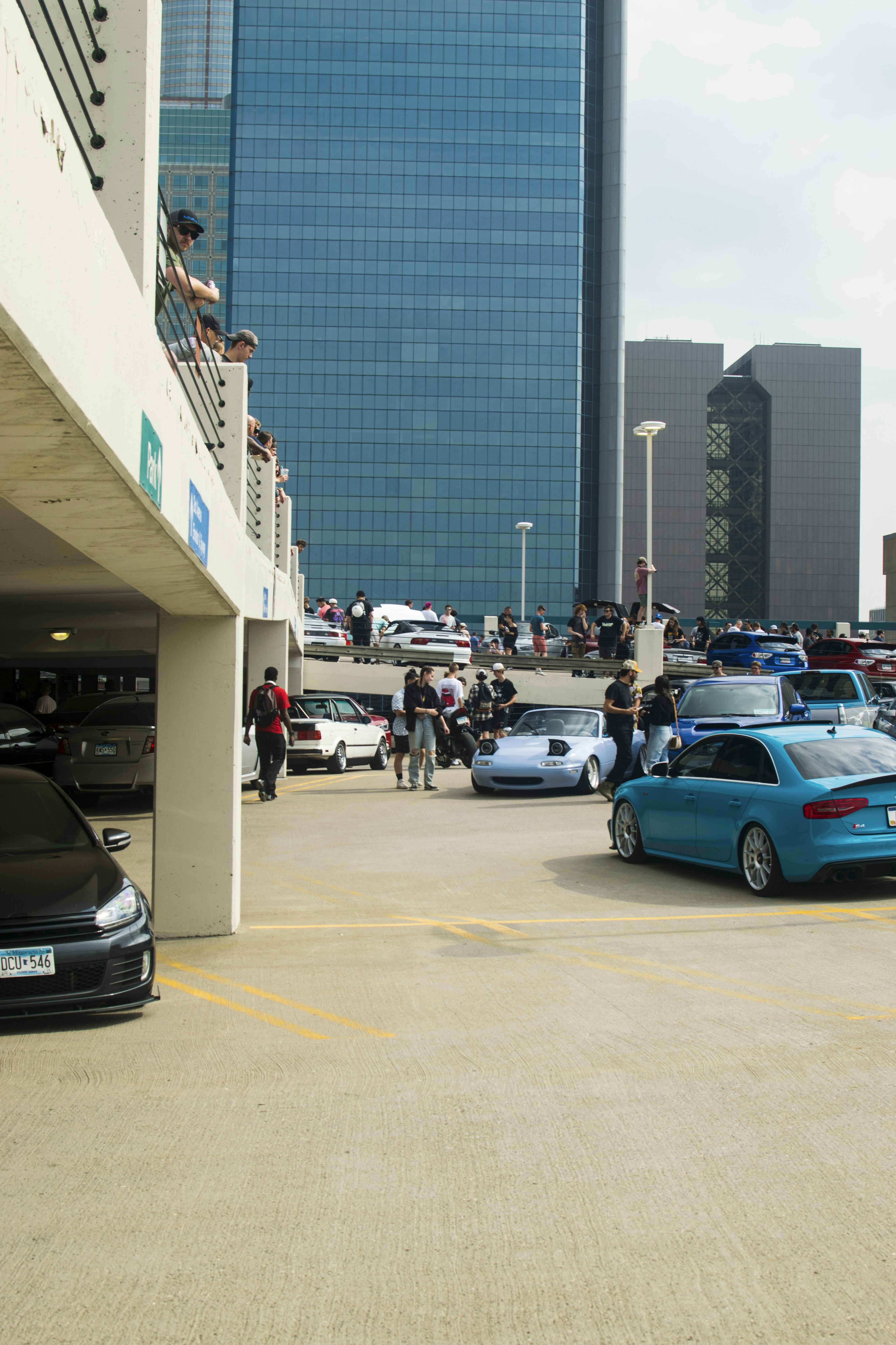 Aerial view of a large car meet with hundreds of modified vehicles in a parking lot on a sunny morning