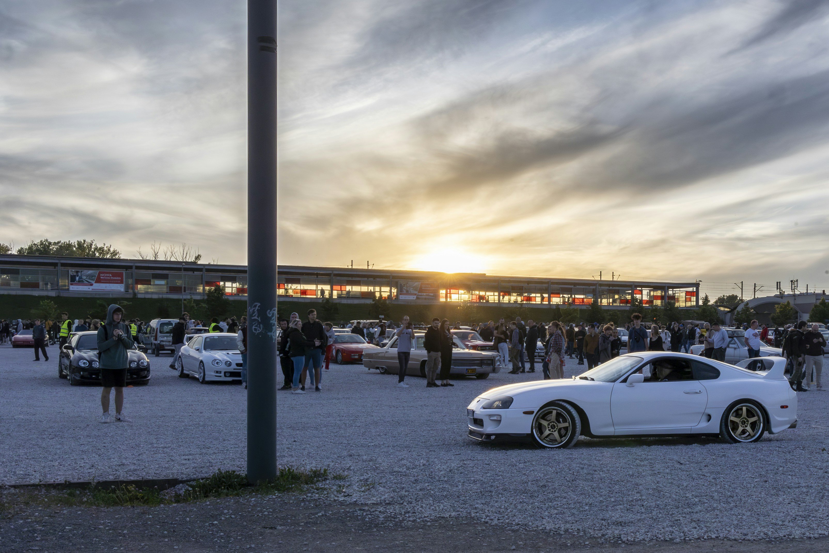 Large group of car enthusiasts gathered around modified vehicles at a Midwest Car Club meet
