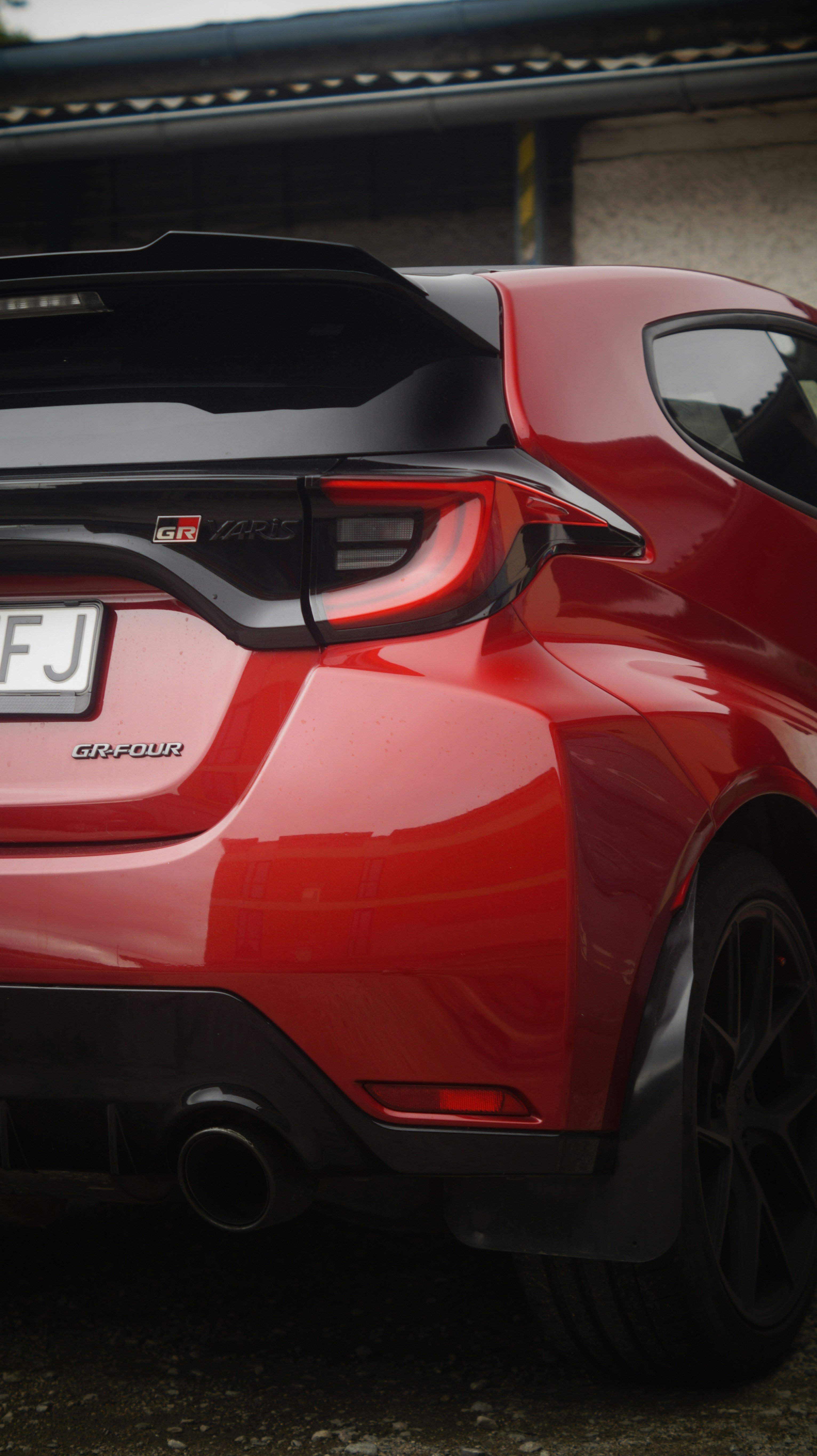 Red Toyota GR Supra with aggressive front splitter and aftermarket exhaust at a car meet