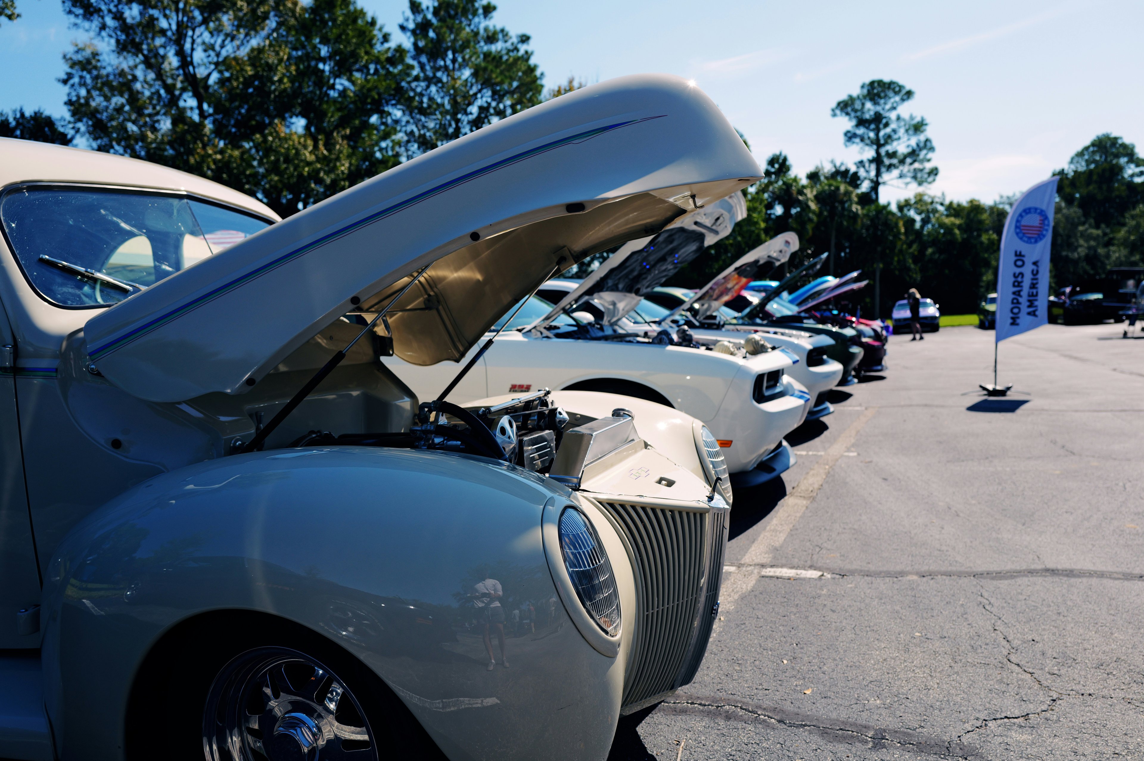 Row of American muscle cars at outdoor car show on sunny day